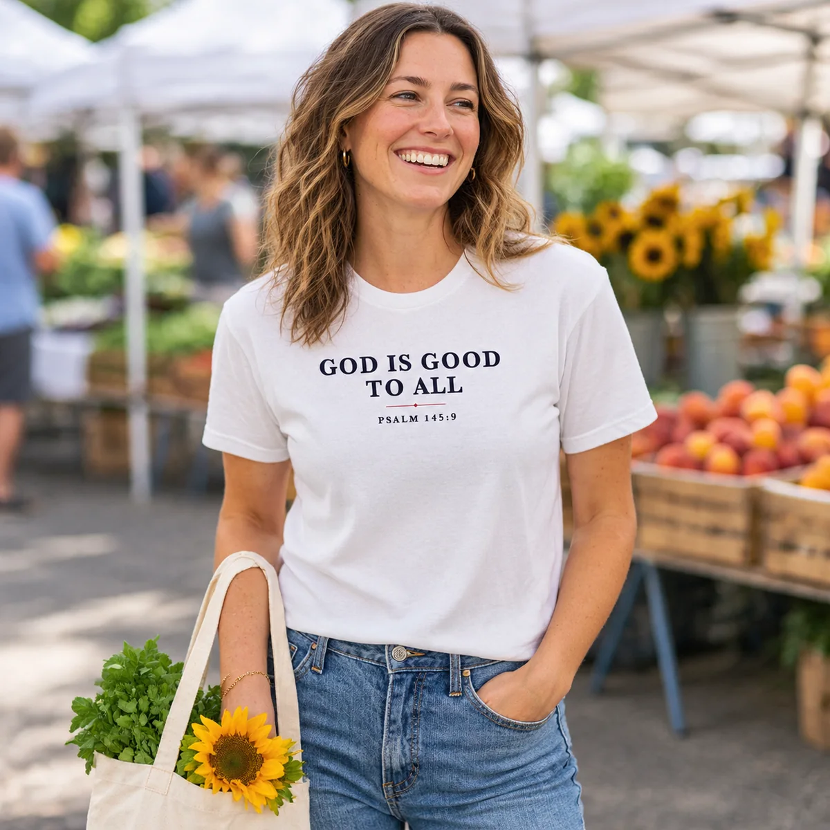 Woman at a farmers market wearing the white God Is Good to All tee