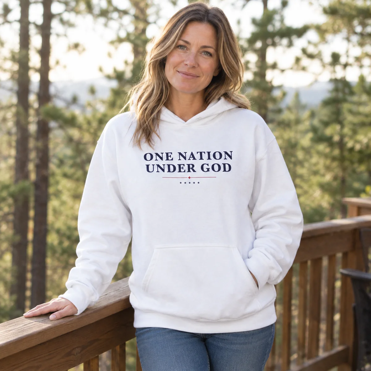 Woman on a wooden deck wearing the white One Nation Under God hoodie